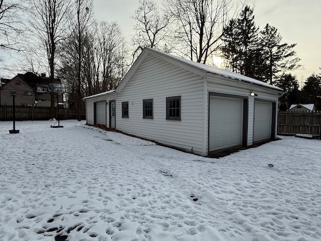 snow covered property featuring an outdoor structure and a garage