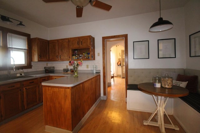 kitchen featuring sink, a center island, hanging light fixtures, light hardwood / wood-style flooring, and decorative backsplash