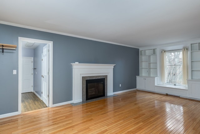 unfurnished living room with crown molding, built in features, and light wood-type flooring