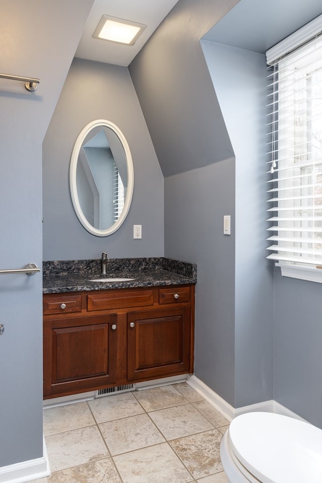 bathroom with vanity, lofted ceiling, tile patterned floors, and toilet