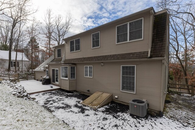 snow covered back of property featuring central AC