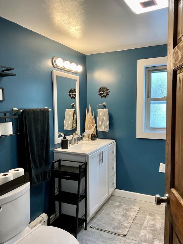 bathroom featuring toilet, baseboard heating, and vanity