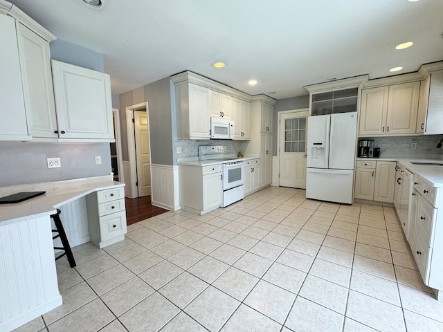 kitchen featuring light tile patterned floors, sink, white cabinets, and white appliances