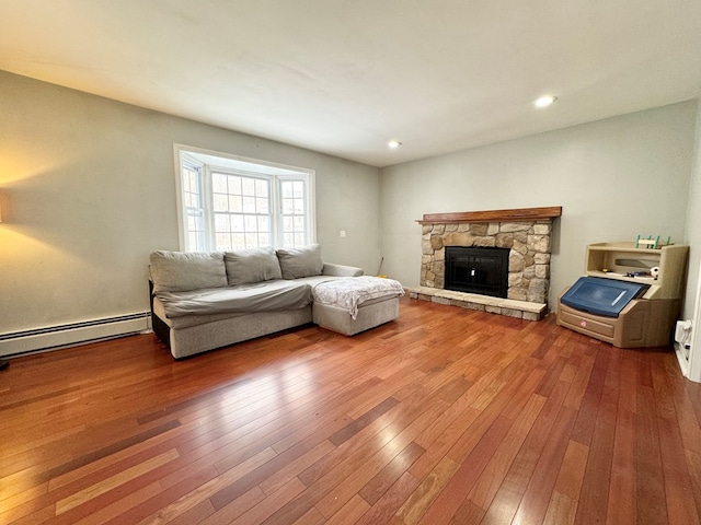 living room featuring a baseboard heating unit, a fireplace, and hardwood / wood-style floors