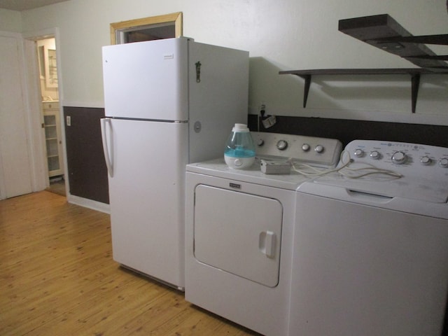 laundry room with independent washer and dryer and light hardwood / wood-style flooring