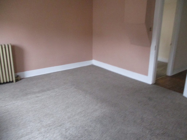 carpeted spare room featuring radiator heating unit