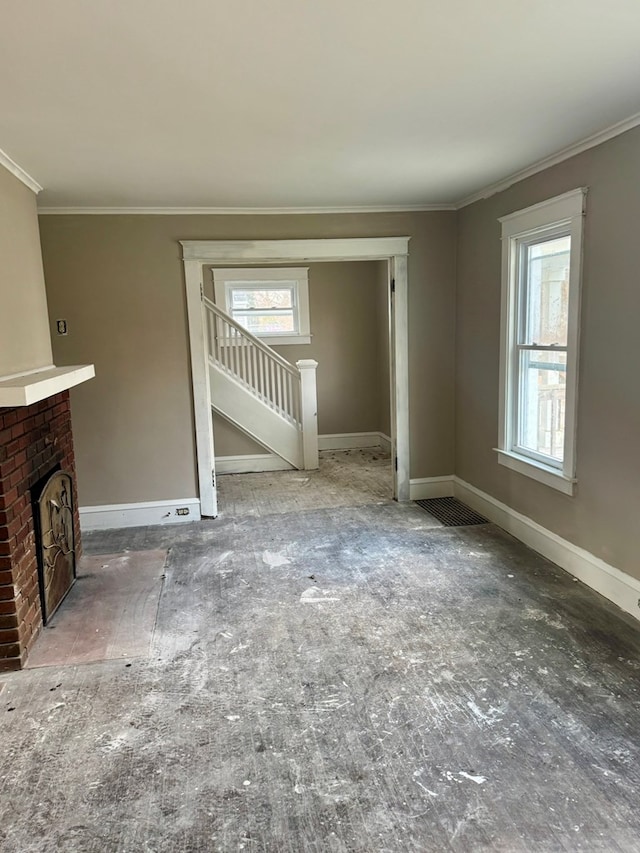 unfurnished living room with ornamental molding, a fireplace, and a wealth of natural light