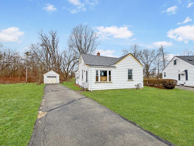 view of front of house featuring a garage, an outdoor structure, and a front yard