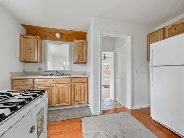 kitchen with light brown cabinetry, ceiling fan, sink, white appliances, and light hardwood / wood-style floors