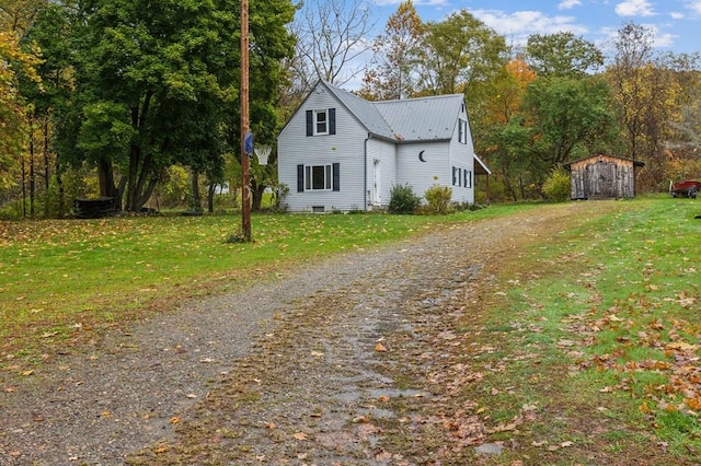 view of front of home featuring an outbuilding, a front yard, metal roof, a shed, and driveway