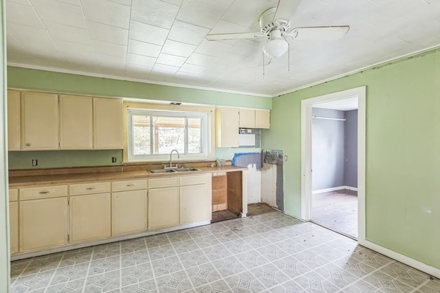 kitchen featuring ceiling fan, a sink, light countertops, cream cabinetry, and light floors