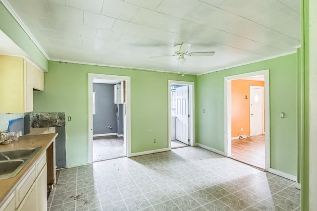 kitchen featuring a sink, light floors, baseboards, and crown molding