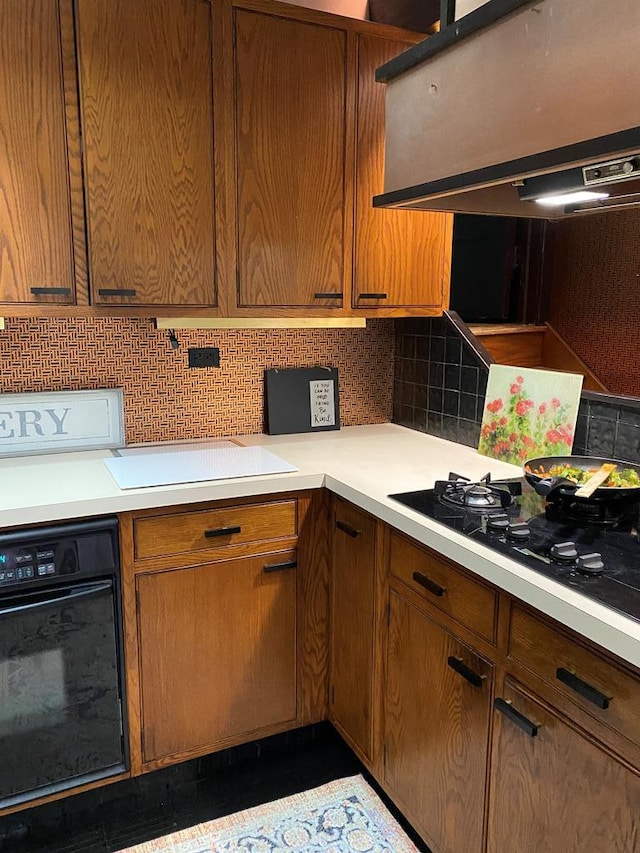 kitchen featuring backsplash, range hood, and black appliances