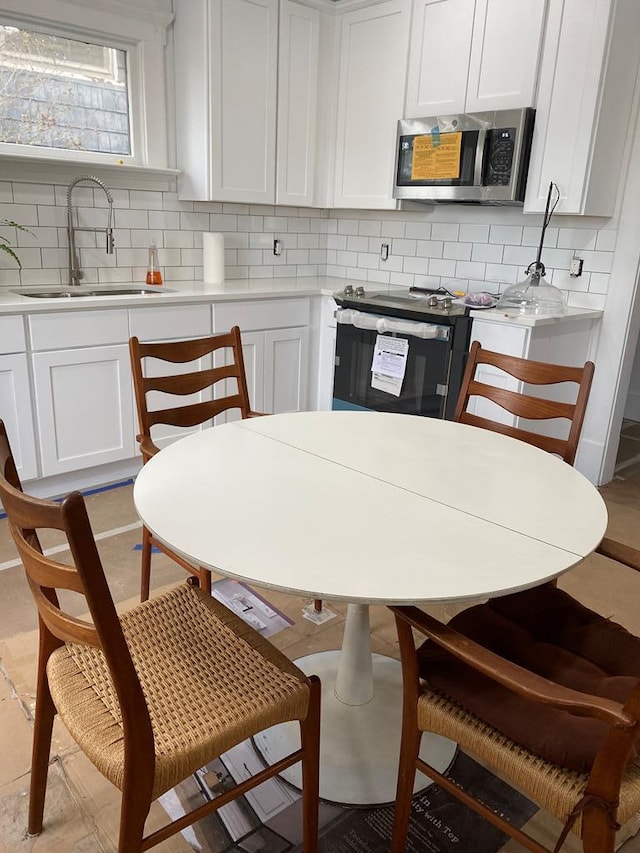 kitchen featuring tasteful backsplash, white cabinetry, range with electric stovetop, and sink