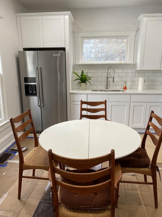 kitchen featuring backsplash, sink, white cabinets, and stainless steel refrigerator with ice dispenser