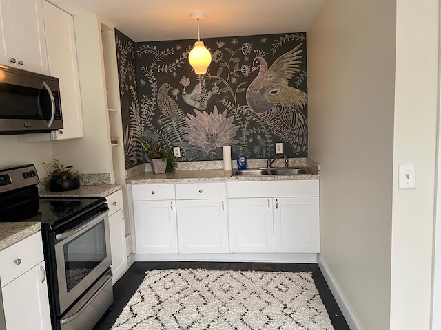 kitchen featuring sink, white cabinets, hanging light fixtures, and appliances with stainless steel finishes