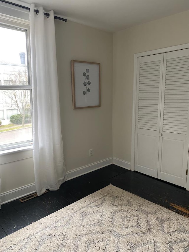 unfurnished bedroom featuring a closet and dark hardwood / wood-style floors