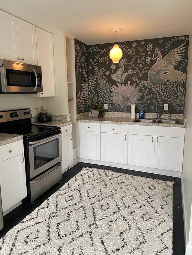 kitchen featuring pendant lighting, white cabinetry, sink, and appliances with stainless steel finishes