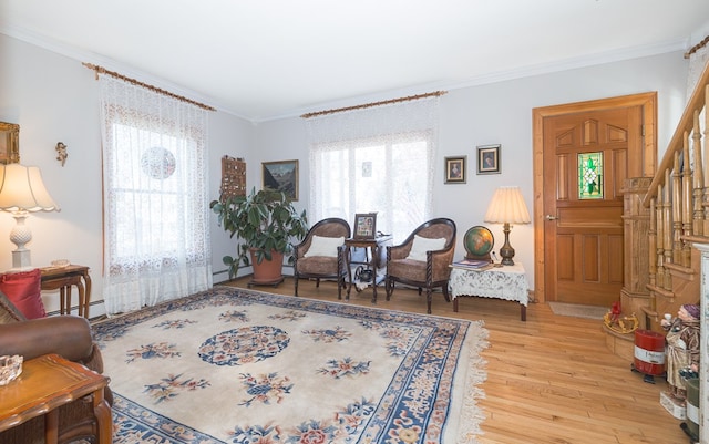 living area featuring light wood-type flooring, ornamental molding, and a baseboard heating unit