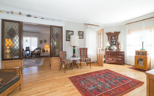 living area with light hardwood / wood-style floors and crown molding