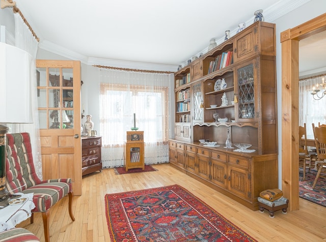 living area with light hardwood / wood-style floors and crown molding