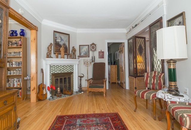 living area with a fireplace, light hardwood / wood-style floors, and ornamental molding