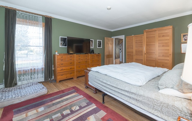 bedroom with light hardwood / wood-style floors and crown molding