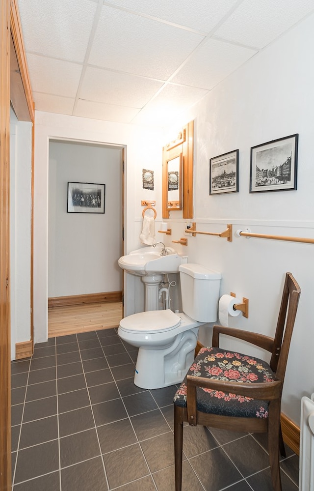 bathroom with a paneled ceiling, tile patterned flooring, and toilet