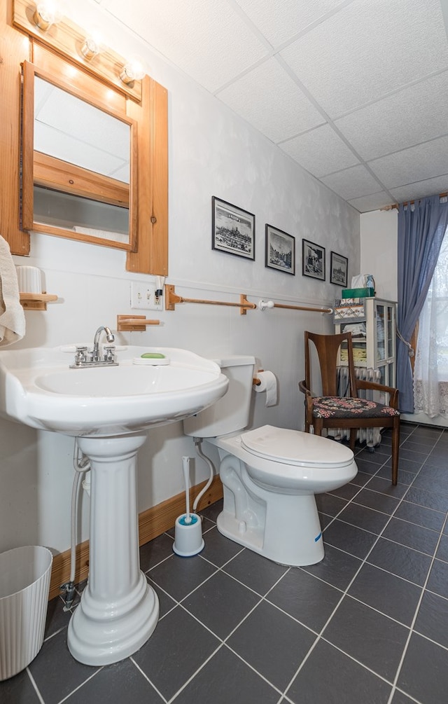 bathroom with tile patterned floors, toilet, a drop ceiling, and sink