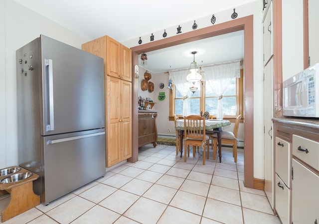 kitchen with stainless steel refrigerator, light brown cabinetry, light tile patterned flooring, and hanging light fixtures