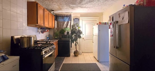 kitchen featuring decorative backsplash, appliances with stainless steel finishes, a textured ceiling, and light tile patterned floors