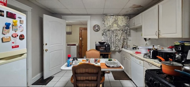 kitchen with light tile patterned flooring, white cabinetry, a drop ceiling, and black appliances