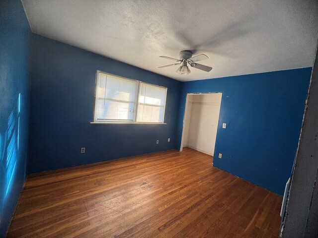 unfurnished bedroom featuring a textured ceiling, dark hardwood / wood-style flooring, and ceiling fan