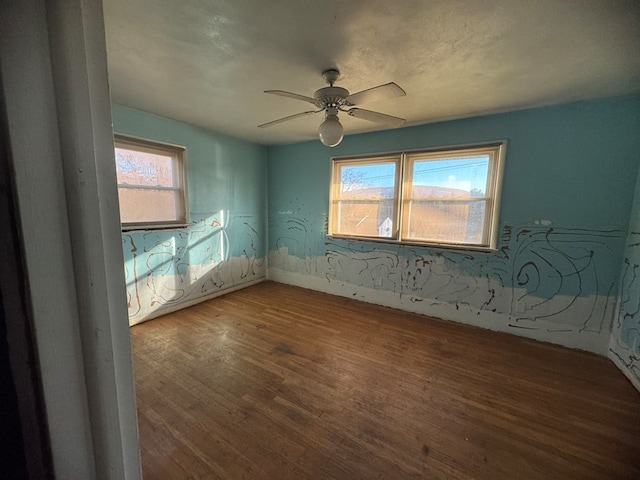 empty room with ceiling fan, a wealth of natural light, and wood-type flooring