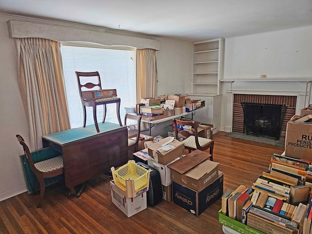 interior space with built in features, dark wood-type flooring, and a brick fireplace