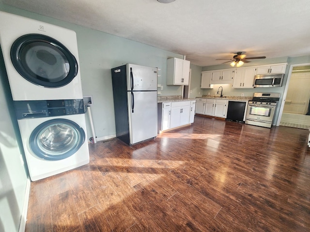 kitchen with dark wood-type flooring, stacked washer / drying machine, sink, appliances with stainless steel finishes, and white cabinets