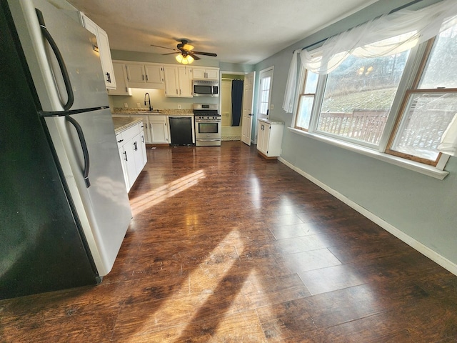 kitchen featuring dark wood-type flooring, sink, white cabinetry, ceiling fan, and stainless steel appliances