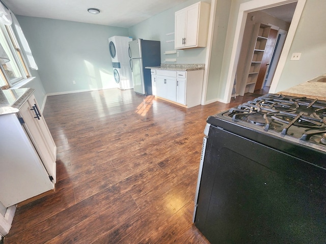 kitchen featuring dark wood-type flooring, stainless steel refrigerator, white cabinetry, light stone countertops, and range with gas stovetop