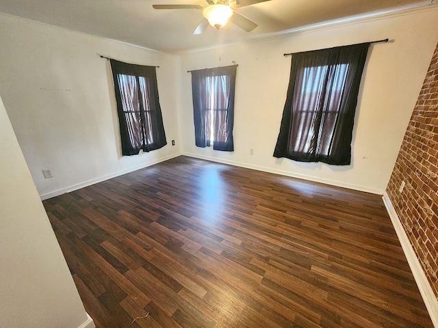 spare room with dark hardwood / wood-style flooring, crown molding, ceiling fan, and brick wall