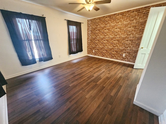 spare room featuring crown molding, dark wood-type flooring, ceiling fan, and brick wall