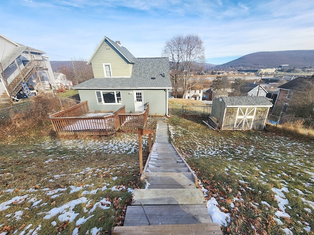 rear view of property featuring a storage shed and a deck with mountain view