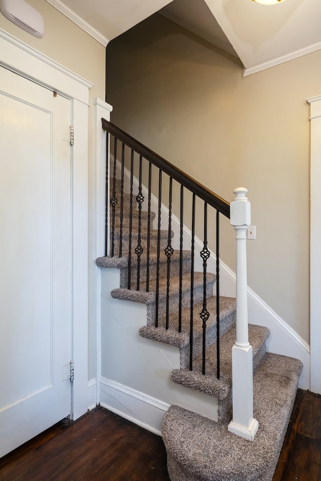 stairs with wood-type flooring and ornamental molding