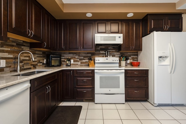 kitchen with white appliances, light tile patterned floors, sink, dark brown cabinets, and tasteful backsplash