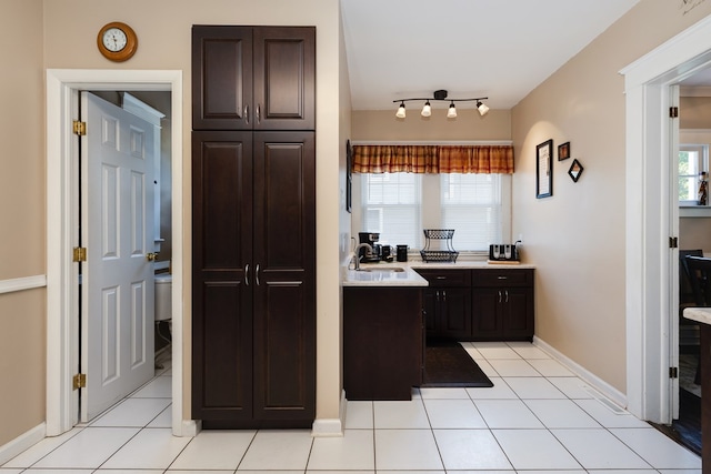 kitchen featuring sink, dark brown cabinets, and light tile patterned floors