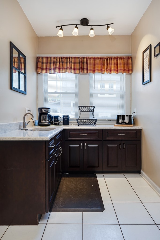 kitchen featuring sink, light tile patterned floors, and dark brown cabinetry