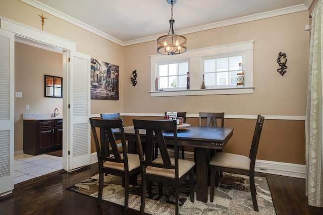 dining area featuring a notable chandelier, crown molding, sink, and wood-type flooring