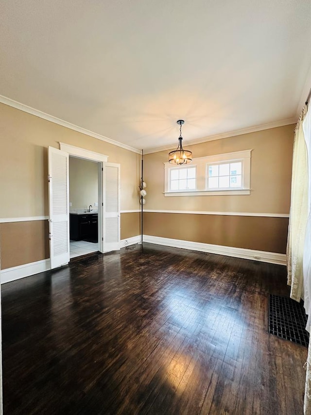 unfurnished room featuring a notable chandelier, crown molding, and dark hardwood / wood-style floors