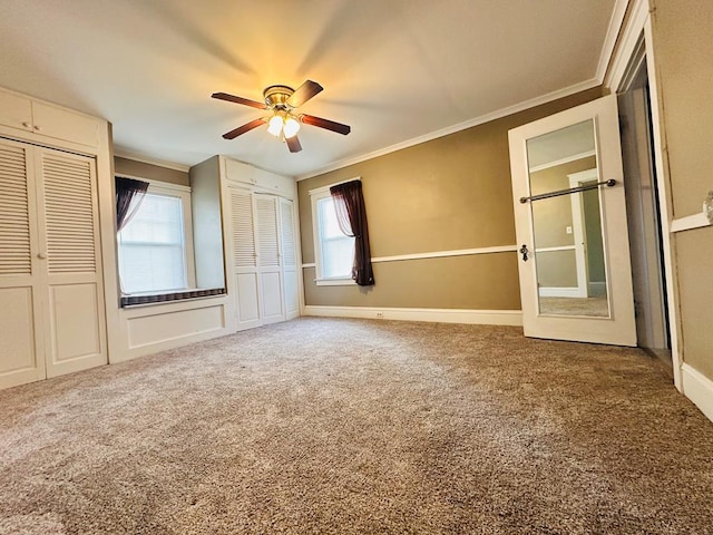 unfurnished bedroom with ceiling fan, ornamental molding, multiple windows, and carpet floors