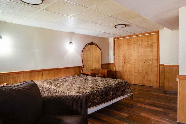 bedroom featuring a drop ceiling, a closet, and dark hardwood / wood-style floors