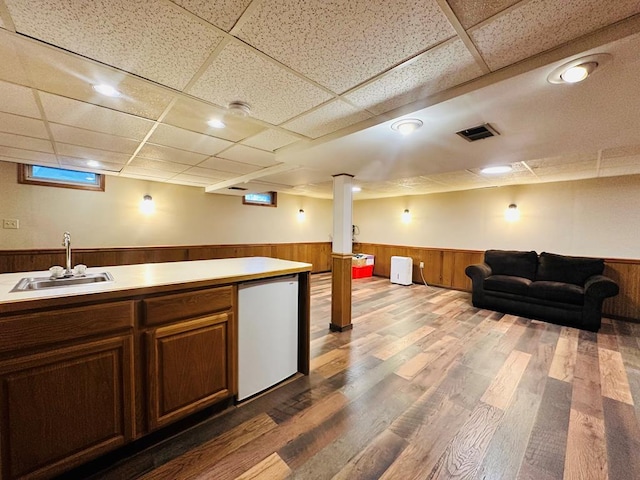 interior space featuring hardwood / wood-style floors, a drop ceiling, refrigerator, and sink